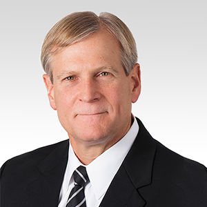 Daniel Doman wearing black suit jacket, white dress shirt and black and white striped tie